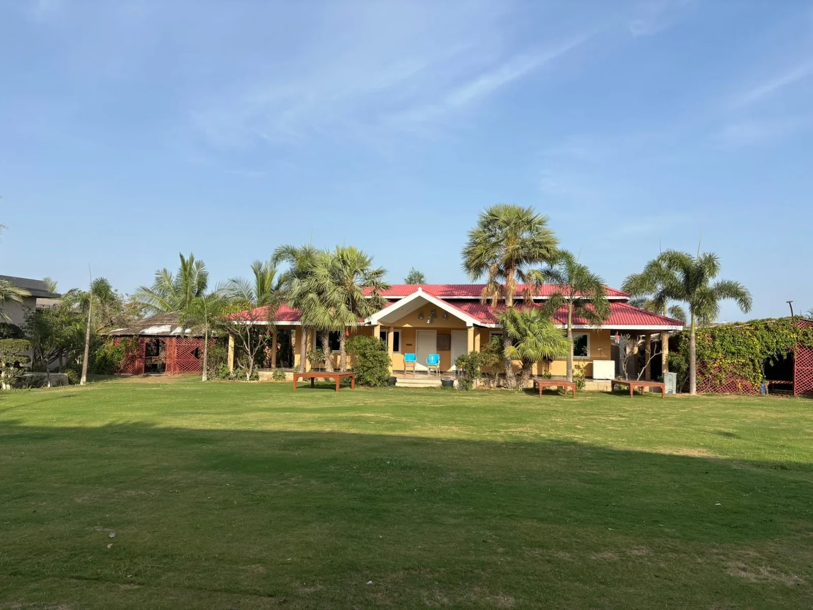 Wide green lawn with red-roof cottages and palms